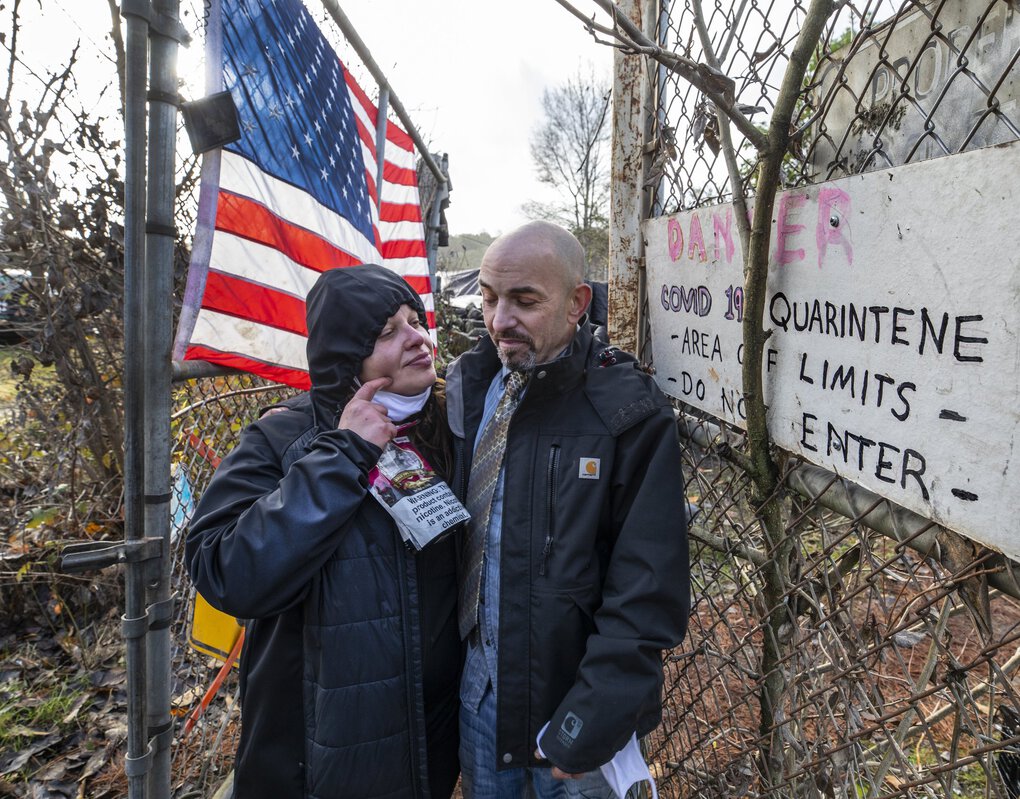  Tish Roth and her husband Imra VanWolvelaere stand at the entrance to a homeless encampment in Seattle where people tested positive and a warning sign was put up by those living in the area.  (Steve Ringman / The Seattle Times)